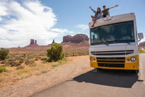  Young couple on top of RV celebrating a road trip.